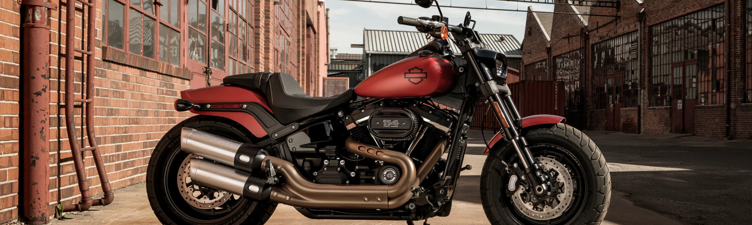 Red 2020 Harley-Davidson® Softail® Fat Bob® motorcycle parked next to a brick building