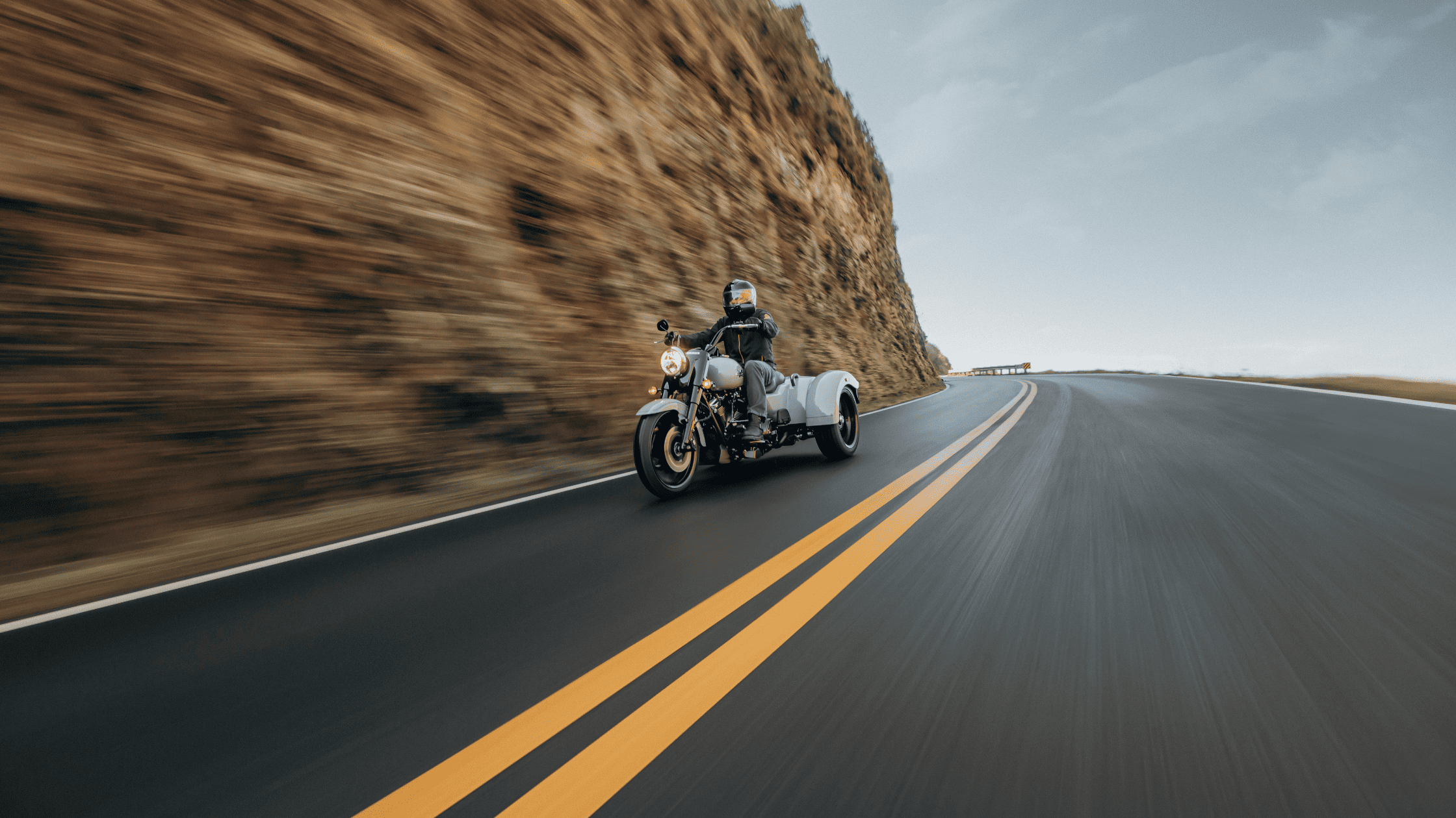 2025 Harley-Davidson® Freewheeler® trike riding on winding mountain road with aggressive front stance