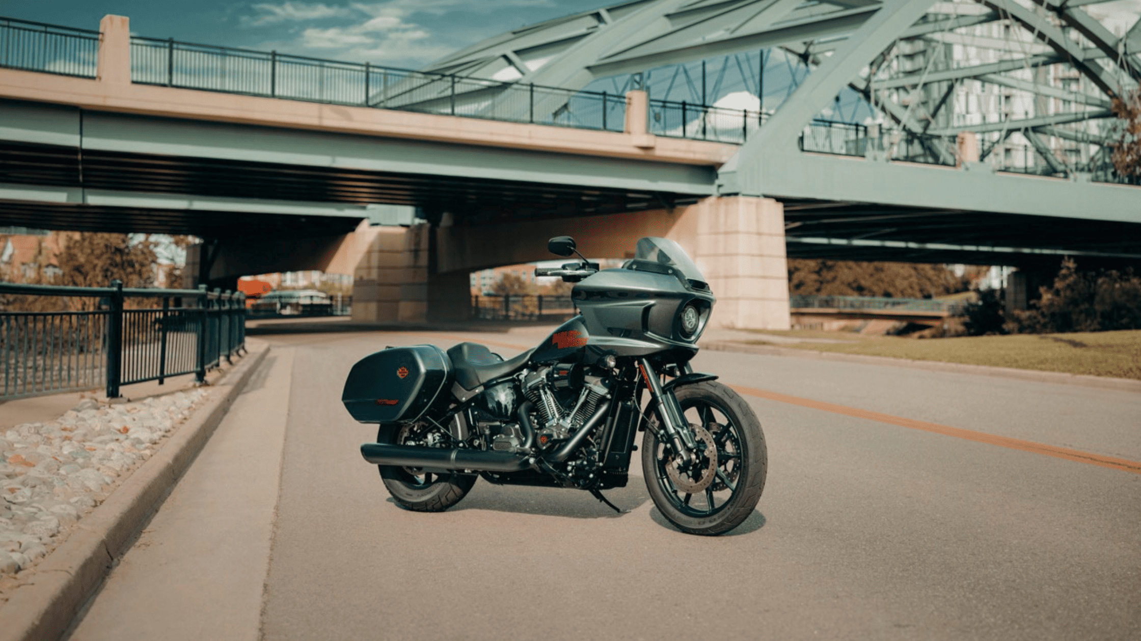 2025 H-D® Low Rider® ST in dark finish with saddlebags parked under steel bridge in the city