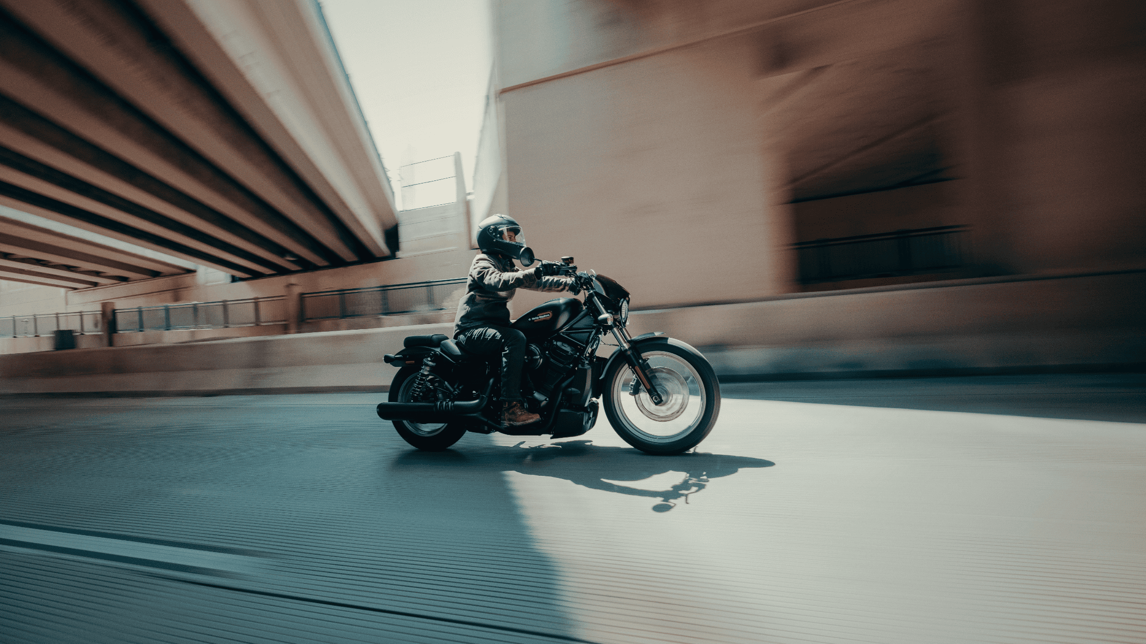 2025 H-D® Nightster® S cruising under an overpass, showing its sleek urban performance design.
