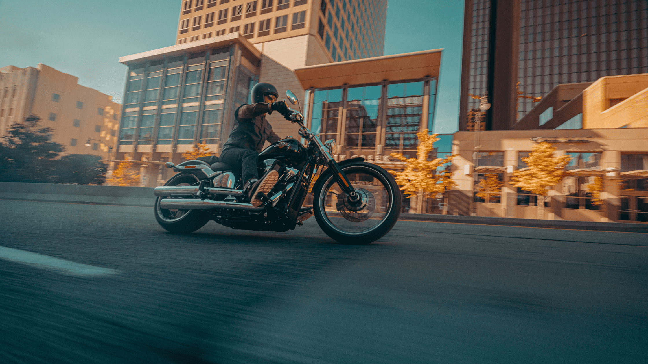 2025 Harley-Davidson® Breakout® cruising through city streets past modern glass buildings.