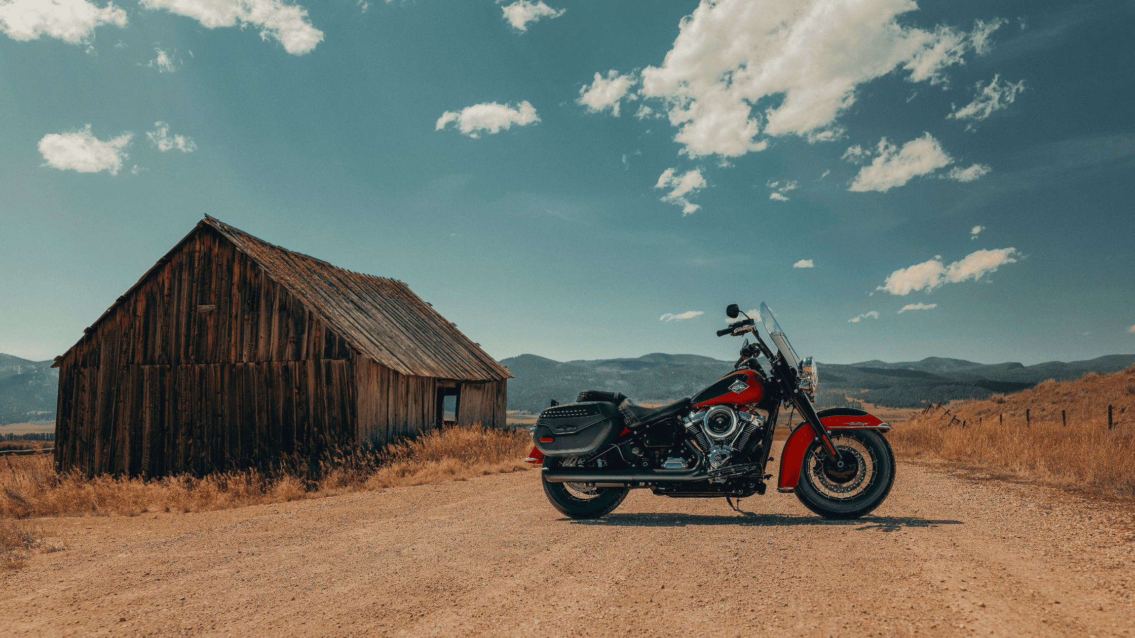 2025 Harley-Davidson® Heritage Classic parked by rustic barn on dirt road in the countryside.