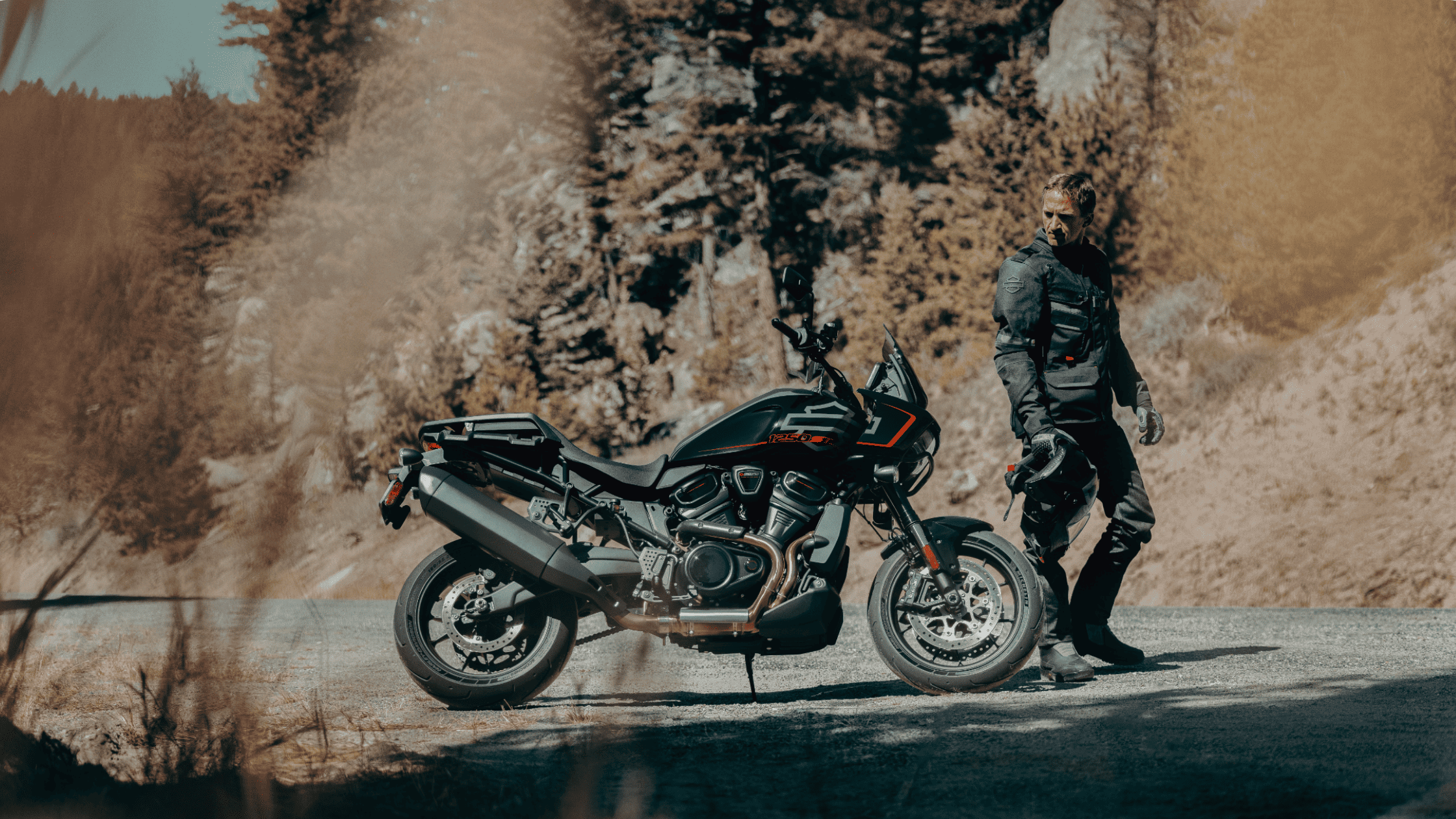 2025 Harley-Davidson® Pan America® 1250 ST in matte black with rider in gear on a rugged mountain ro…