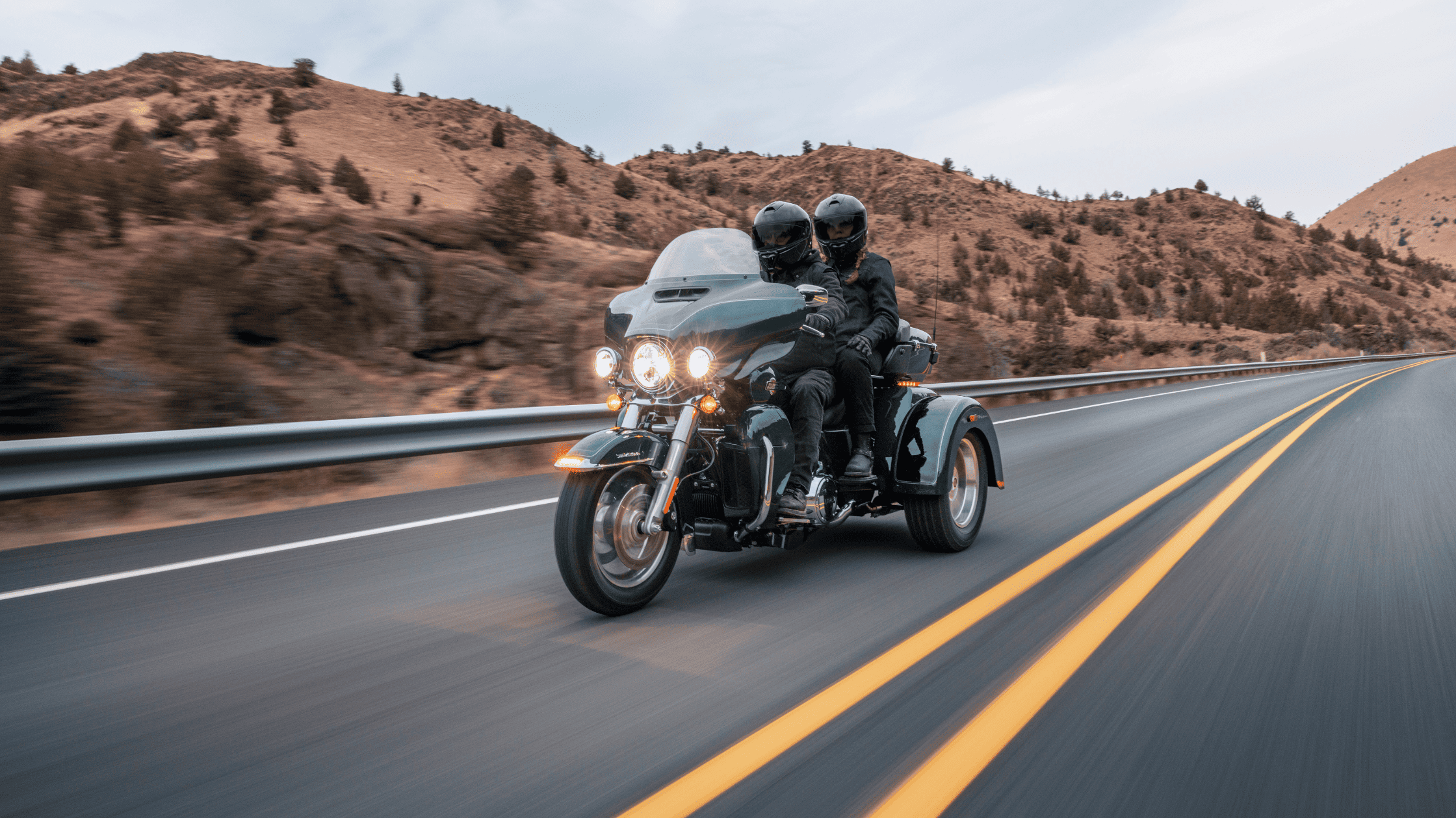 2025 Harley-Davidson® Tri Glide® Ultra trike riding on highway with passenger and full touring setup