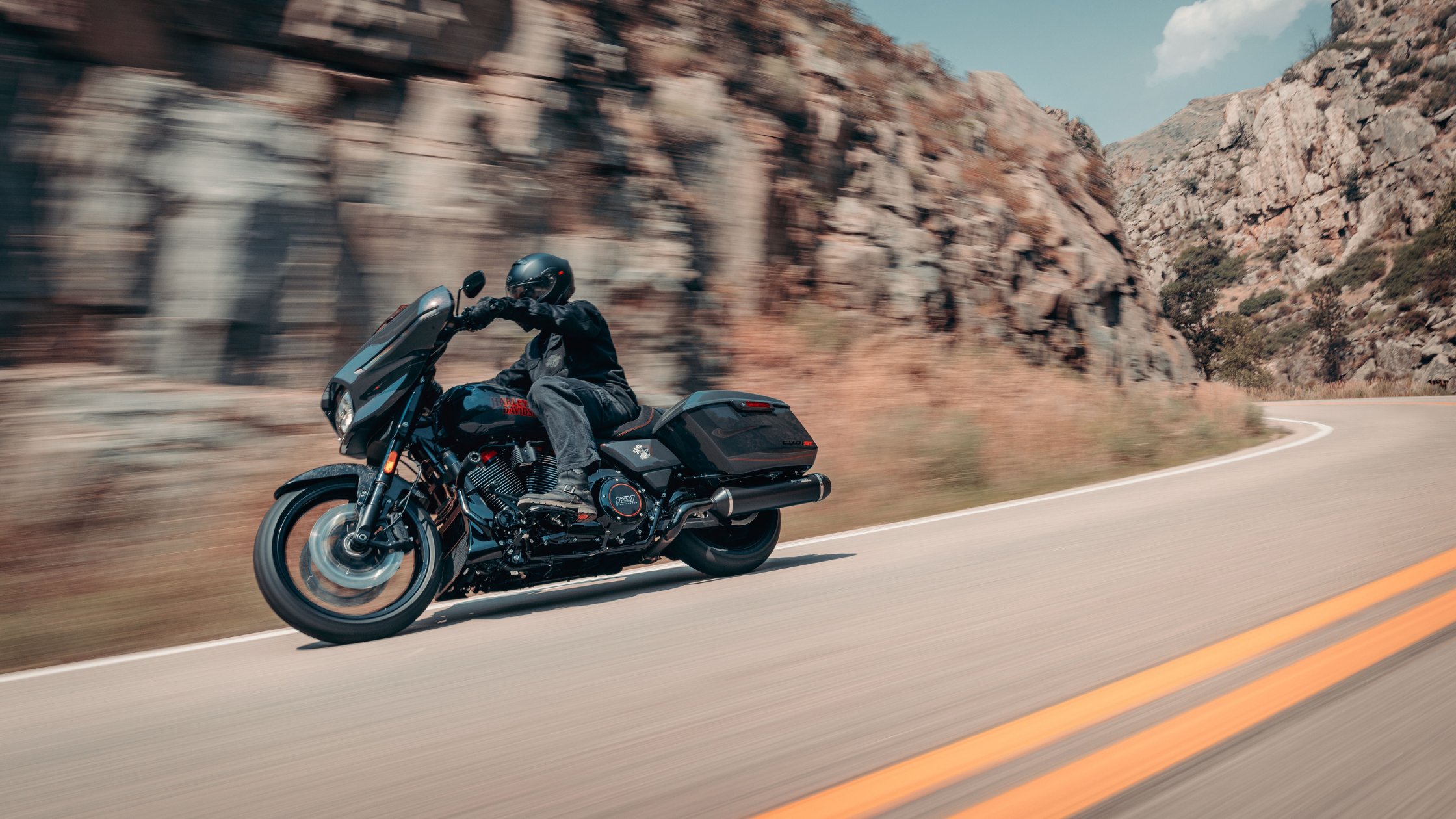 Black 2026 H-D® CVO™ Street Glide® ST leaned into a canyon road with rocky cliffs in the background