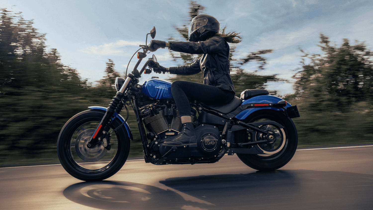 2024 Harley-Davidson&reg; Street Bob&reg; 114 in motion, rider on an open road, showcasing sleek design and...