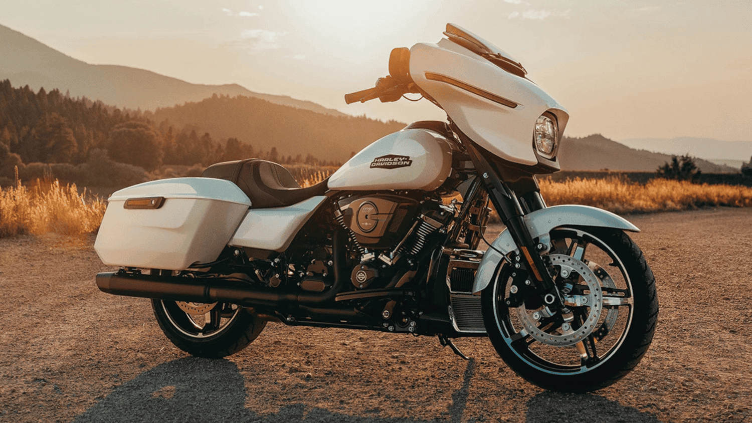 A stunning white 2025 Harley-Davidson&reg; Street Glide&reg; set against a scenic countryside sunset backdro...