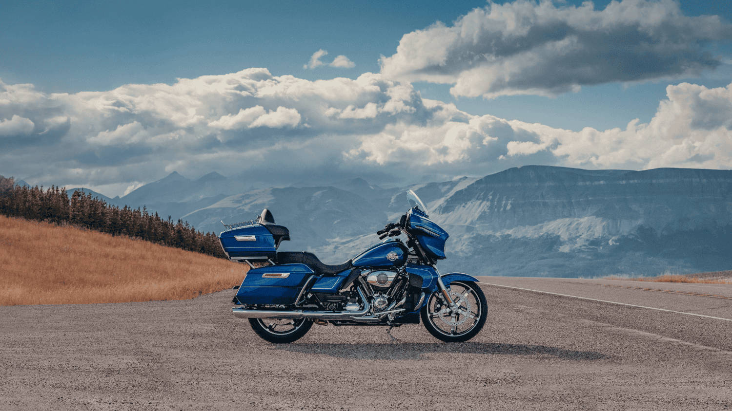 A blue 2025 Harley-Davidson&reg; Street Glide&reg; Ultra parked on a scenic road, mountains in the background.